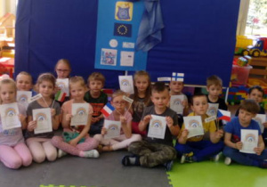 Grupa starszaków pozuje do zdjęcia ze zdobytymi Dyplomami Europejczyka i flagami państw odwiedzonych przez nich na zajęciu.